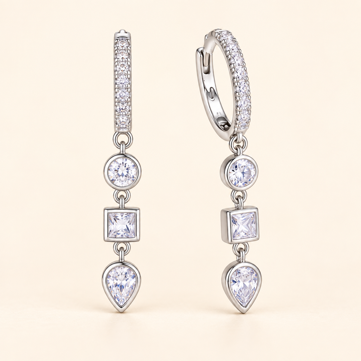 Amaya three-stone drop huggie earrings close-up: pavé huggie hoops with a three-stone clear CZ drop, Dubai