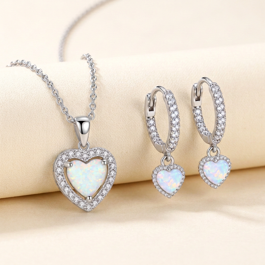Elara sterling silver opal heart halo necklace and matching heart-drop huggie earrings on a cream background