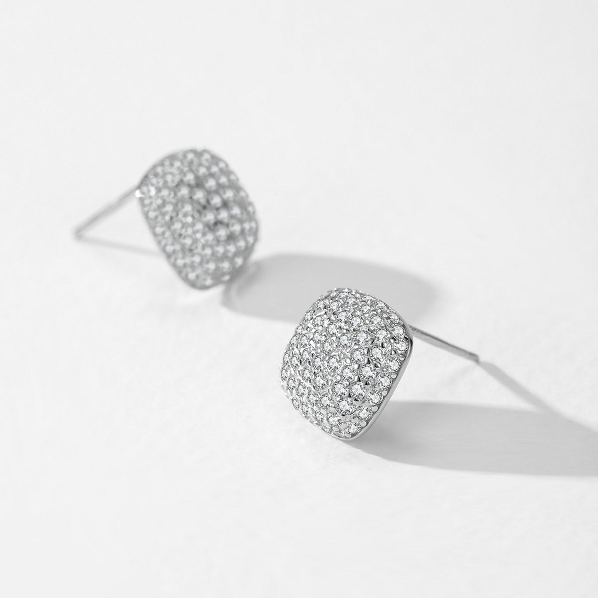 Solenne cushion pavé CZ stud earrings close-up: domed cushion-square studs covered in tiny CZ, 925 sterling silver, Dubai